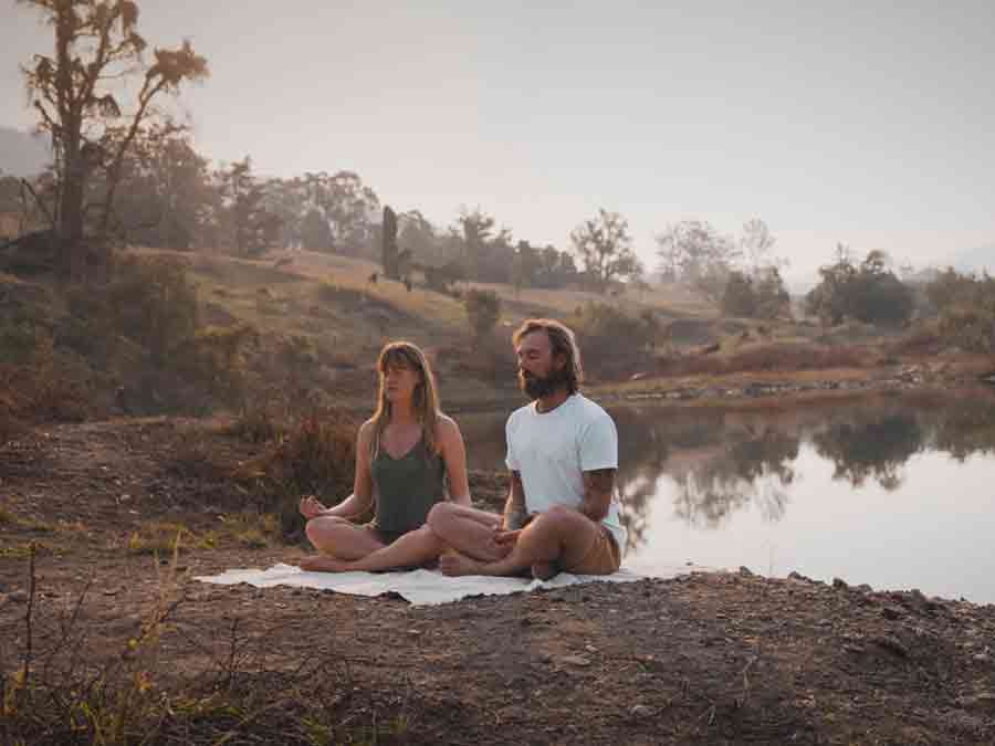 Couple meditating by lake