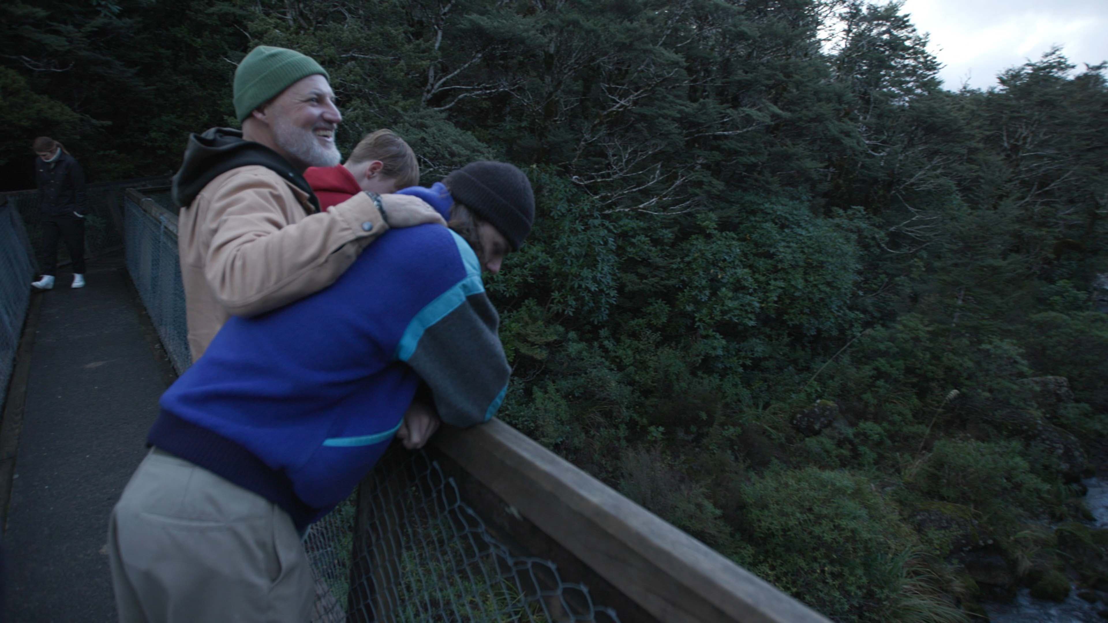 Father and sons looking over bridge