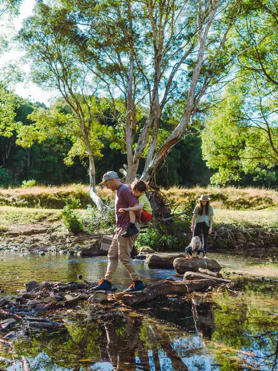 Father stepping through stream with son on back