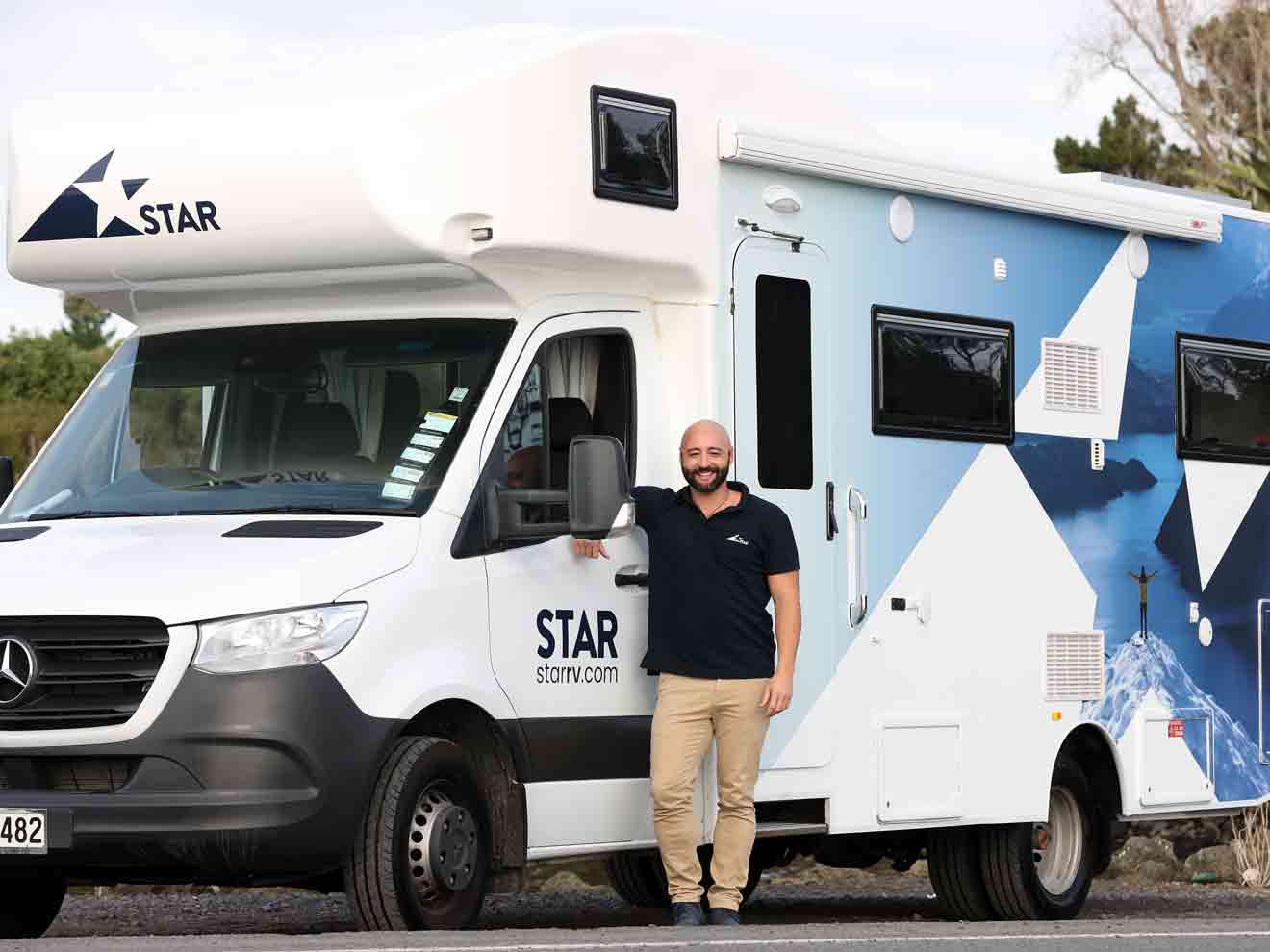 Man in blue top standing outside motorhome