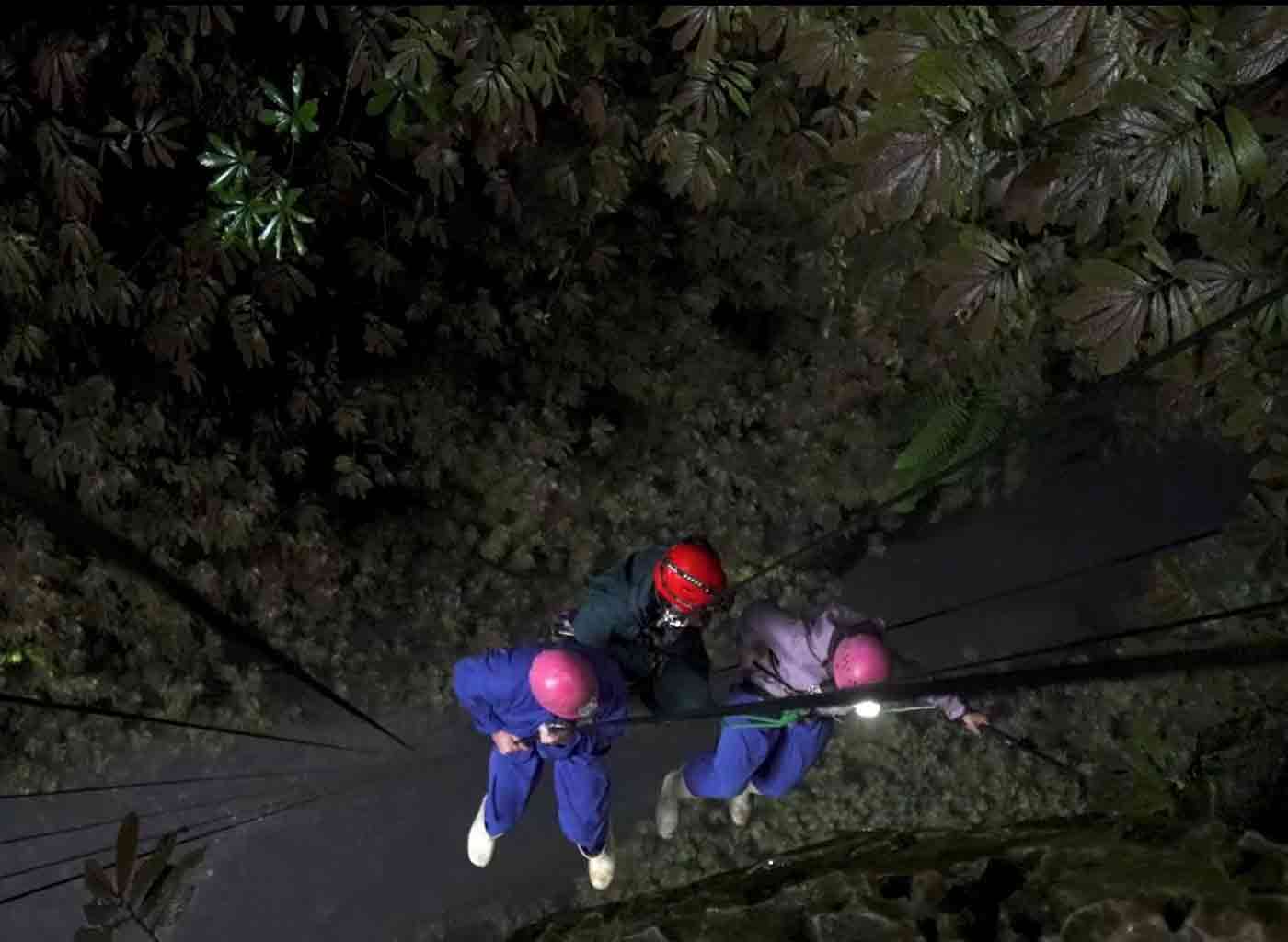 Three people abseiling in New Zealand underground caves