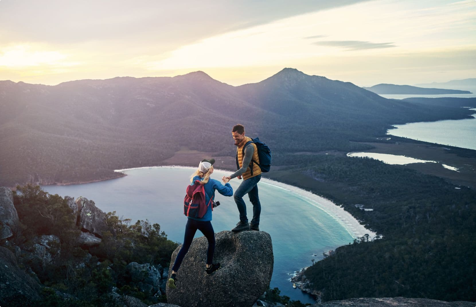Couple reaching top of mountain